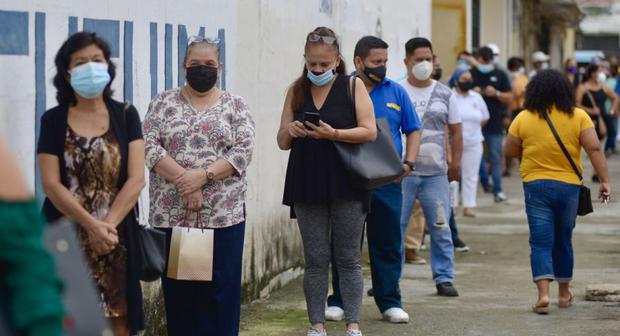 Varias personas acuden a un centro de votación en el colegio Calicuchima con doble mascarilla y un visor para protegerse del COVID-19, hoy, en Guayaquil (Ecuador). (EFE/ Marcos Pin). 