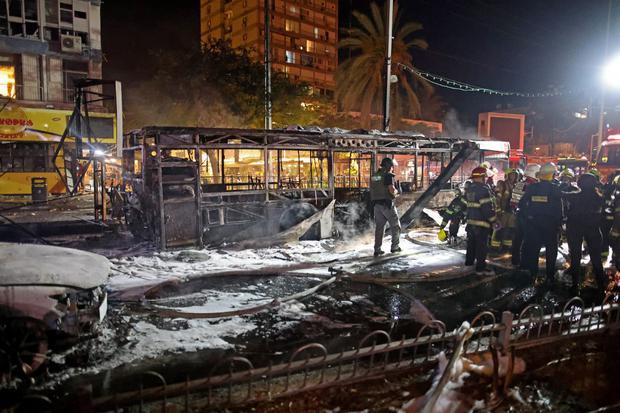 Los bomberos revisan un autobús quemado en la ciudad israelí de Holon, cerca de Tel Aviv, el 11 de mayo de 2021. (Ahmad gharabli / AFP).